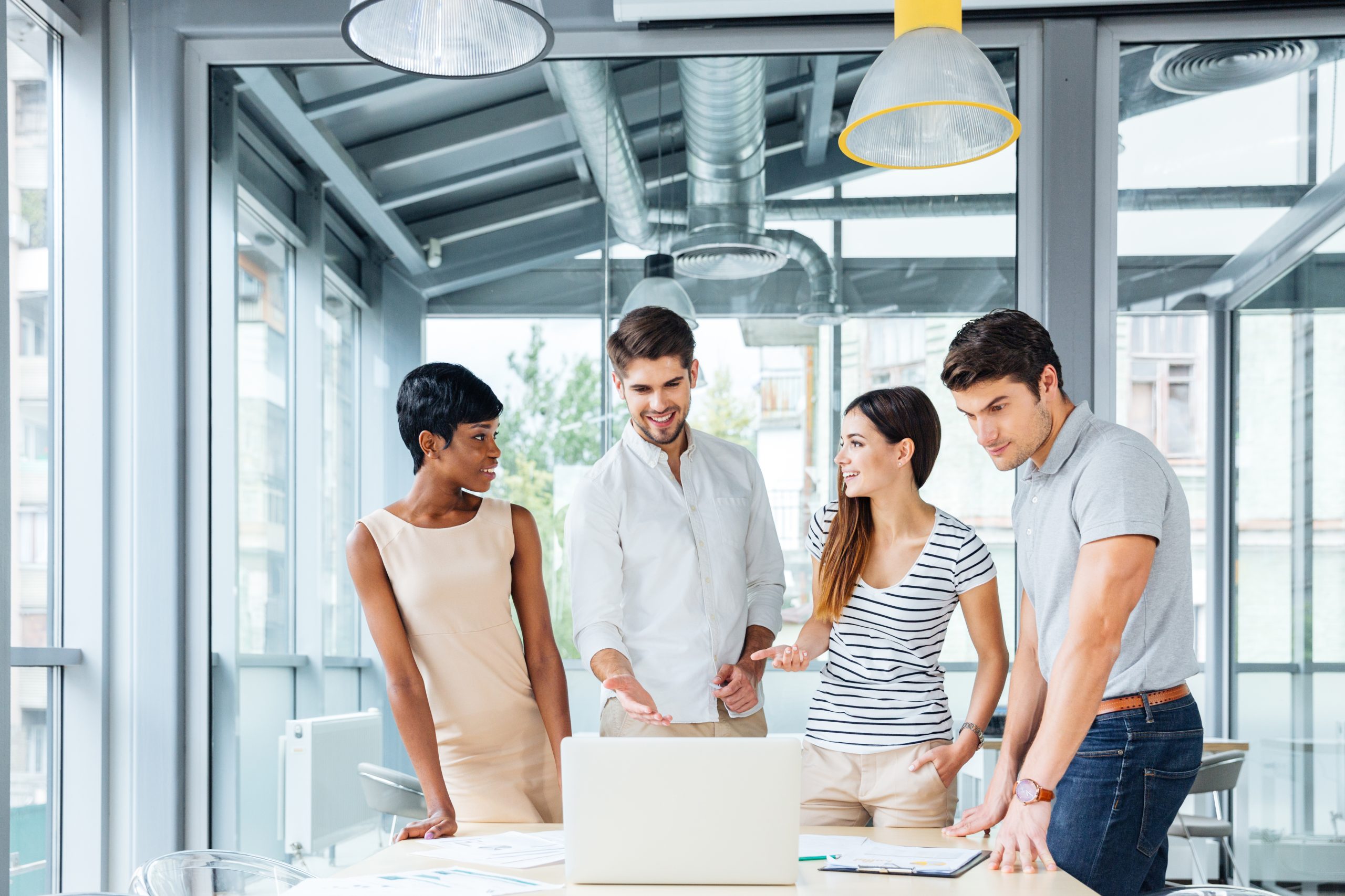 graphicstock group of cheerful successful business people with laptop standing and talking together in office r kexGHXShx scaled