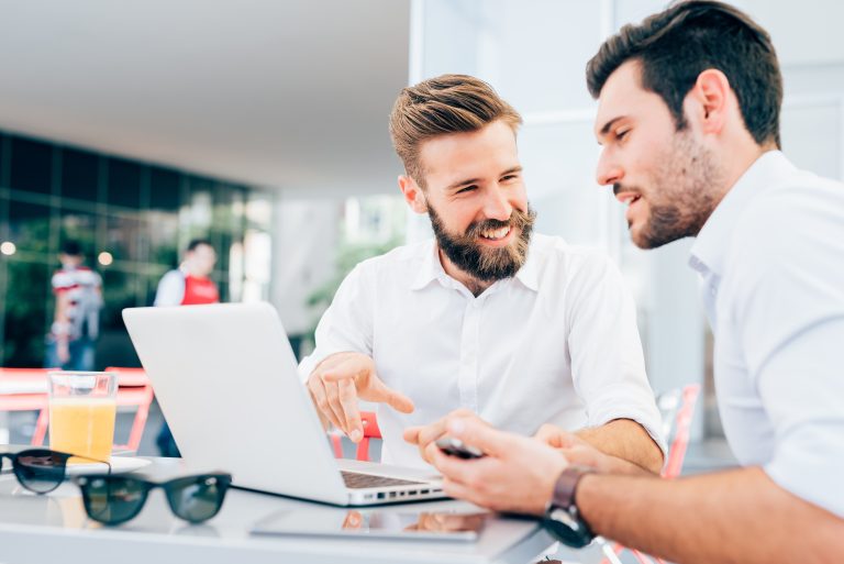 graphicstock two young bearded caucasian modern business man sitting in a bar using laptop looking each other smiling and chatting business work technology concept H6NTVglqyb